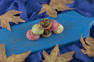 bunte süße kleine Donuts auf einem blauen Holzbrett foto