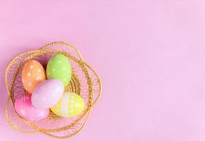 glücklich Ostern Urlaub Gruß Karte Konzept. bunt Ostern Eier und Frühling Blumen auf Pastell- Rosa Hintergrund. eben legen, oben Sicht, Kopieren Raum. foto