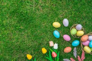 glücklich Ostern Urlaub Gruß Karte Konzept. bunt Ostern Eier und Frühling Blumen auf Grün Gräser Hintergrund. eben legen, oben Sicht, Kopieren Raum. foto