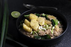 Ananas gebraten Reis hat gehackt Schweinefleisch und Gemüse im Teller auf Stein Tisch. foto