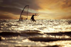 Silhouette Fotografie von Mann spielen Drachen Surfen und Wind Surfen Über eilen Meer Niveau gegen schön Sonnenuntergang Himmel foto