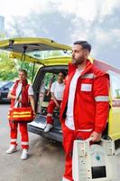 Sanitäter Krankenschwester und Notfall Arzt beim Krankenwagen mit Bausatz. ein Sanitäter, Stehen beim das Rückseite von ein Krankenwagen, durch das öffnen Türen. foto