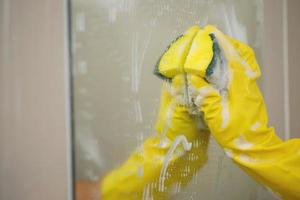 Hausfrau Reinigung das Spiegel im das Badezimmer foto