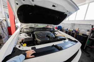 Muskel Auto mit öffnen Kapuze beim Bedienung Reparatur Bahnhof im Aufzug. Hand von Inhaber Mann auf Es. foto