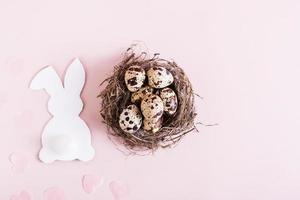 glücklich Ostern Nest mit Wachtel Eier und Weiß Karton Hase auf Rosa Hintergrund oben Aussicht foto