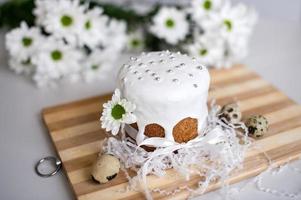 Ostern Kuchen im Glasur mit ein Band steht auf ein Tafel mit Wachtel Eier und Weiß Blumen foto