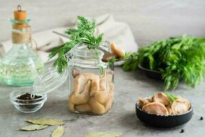 eingelegt Pilz auf ein Gabel auf ein Krug mit Steinpilz und Dill und im ein Glas Krug auf das Tisch. Vegetarier organisch Lebensmittel. foto