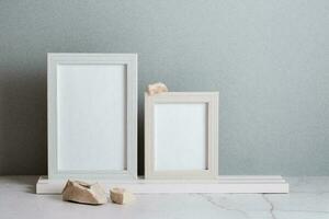 Öko freundlich Zuhause Dekor zwei Foto Frames und Steine auf das Tabelle auf ein grau Hintergrund. Pastell- Schatten