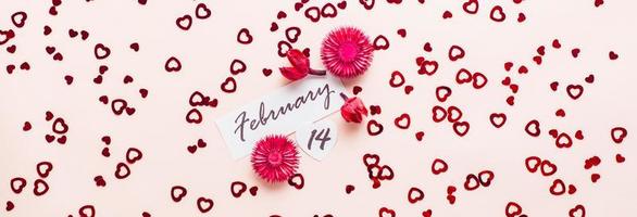 Valentinstag Tag. Datum von Februar 14 und trocken Blumen auf ein Rosa Hintergrund übersät mit Herzen. oben Sicht. Netz Banner foto