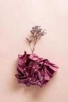 das Konzept von Depression und Stagnation. trocken Blume von ein Bündel von Papier auf ein Rosa Hintergrund. Vertikale Aussicht foto