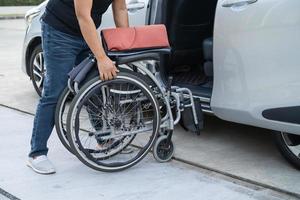 asiatisch Behinderung Frau auf Rollstuhl bekommen im ihr Auto, Barrierefreiheit Konzept. foto
