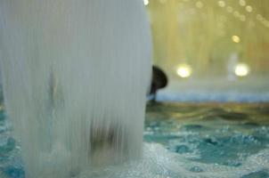 verschwommen Wasser Hintergrund. von hinten beleuchtet Wasser Jet im das Brunnen. foto