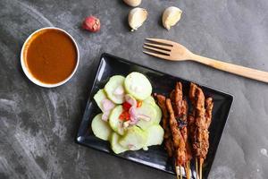 Hähnchen Satay oder stillen Ayam serviert mit lange, Reis Kuchen und Erdnuss Soße. foto