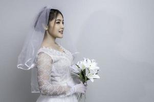 Porträt von asiatisch Frau tragen Braut mit Blume auf Weiß Hintergrund, Hochzeit Konzept foto