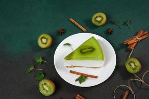 Käsekuchen mit Kiwi, Zimt Stock und Blätter Minze auf ein Grün Hintergrund. Kopieren cpase zum Text foto