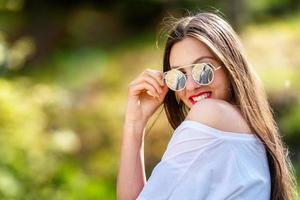 Außenporträt der schönen, emotionalen, jungen Frau in der Sonnenbrille foto
