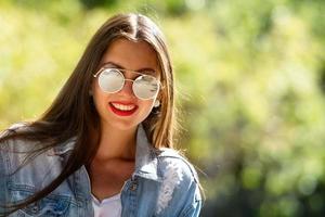 Außenporträt der schönen, emotionalen, jungen Frau in der Sonnenbrille foto