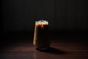 Eiskaffee mit Milch auf dem Tisch auf dunklem Hintergrund