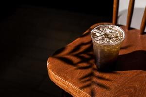 Glas Eiskaffee auf einem Stuhl mit Schatten foto