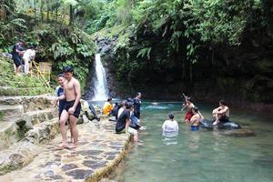 bogor Indonesien März 2023 männlich und weiblich Touristen sind spielen im das Wasser beim Curug Pangeran Wasserfall foto