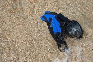 Flossen zum Schwimmen und ein Maske zum Schnorcheln auf das Strand. Welle und Sand. Marine Unterhaltung. ausruhen. foto