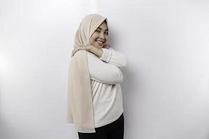 jung schön asiatisch Muslim Frau tragen ein Kopftuch Über Weiß Hintergrund umarmen Sie selber glücklich und positiv, lächelnd zuversichtlich. Selbstliebe und Selbstpflege foto