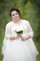 Fett Braut mit ein Hochzeit Strauß auf ein Sommer- Hintergrund. foto