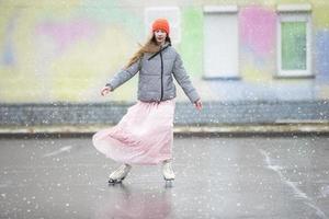 Mädchen Teenager Rollschuhe auf Eis im das stadt.jung Mädchen im ein lange Kleid und ein warm Jacke auf das Eis. foto