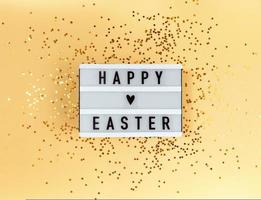 fröhlicher Ostergruß auf einem Leuchtkasten und Konfetti auf gelbem Hintergrund foto