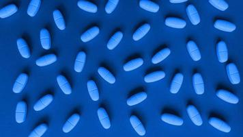 Tablettenkapseln auf einem blauen Hintergrund, monochromes einfaches flaches lag mit medizinischem Konzept der Pastellstruktur foto