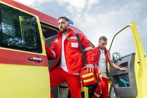 Sanitäter Krankenschwester und Notfall Arzt beim Krankenwagen mit Bausatz. ein Sanitäter, Stehen beim das Rückseite von ein Krankenwagen, durch das öffnen Türen. foto