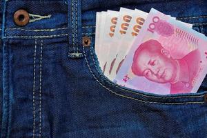 Yuan oder rmb und thailändisch baht im Jeans Tasche foto