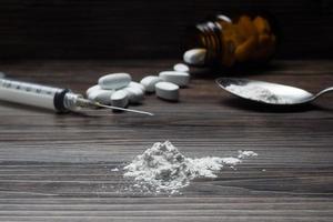 Drogen einstellen - - Pulver und Tabletten und Spritze auf hölzern Hintergrund foto