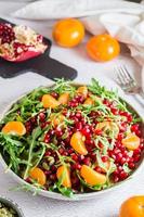Obst Vitamin Salat von Granatapfel, Mandarine, Rucola und Kürbis Saat im ein Teller auf das Tisch. organisch Vegetarier Lebensmittel. Vertikale Sicht. Nahansicht foto