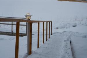 Laterne auf einem schneebedeckten Weg mit Holzgeländern im Winter foto