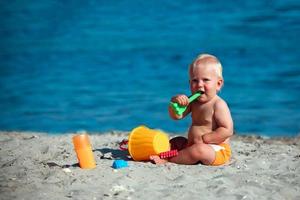 Kleinkind Sitzung auf das Strand und spielen mit Plastik Spielzeuge im das Sand. foto