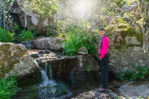 Frau Wanderer Nächster zu ein Wasserfall auf das Fluss foto