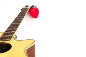 Akustikgitarrenhals und rotes Herz vor weißem Hintergrund. Liebes- und Musikkonzept. foto