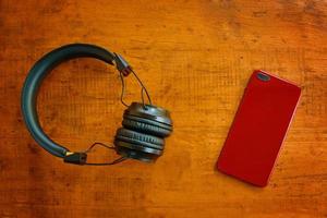 Draufsicht von Kopfhörern und Smartphone auf Holztisch foto
