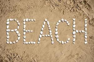 Strand - - Wort gemacht mit Steine auf Sand foto