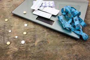 Messung Band, Tabletten und Waage auf hölzern Hintergrund. das Konzept von Diät Pillen. foto