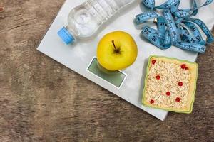 Waage, Messung Band, Apfel, Haferflocken, Wasser auf alt hölzern Hintergrund. Konzept von richtig Ernährung. foto