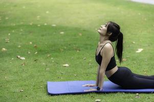 asiatisch schlank Frau Übung allein im das parken, müde von trainieren, spielen Yoga Konzept foto