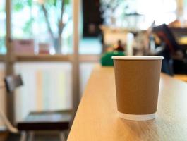 einer Kaffee Tasse Papier platziert auf ein hölzern Tisch, im ein Cafe Kaffee Geschäft Getränke sind verfügbar. heiß Innerhalb zum wegbringen bereit zu trinken, erfrischend. Aroma Erwachen frisch zu Arbeit platziert foto