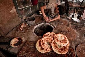 ein alt Verkäufer Verkauf gebacken Naan auf das alt Straße von Kashgar foto