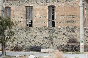 alt Backstein Mauer mit zwei Fenster und ein hölzern Schubkarre. foto