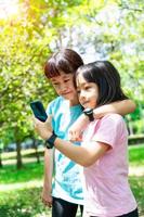 zwei Schwestern umarmen während mit Handy, Mobiltelefon Telefon im das Park. glücklich Familie Konzept. foto