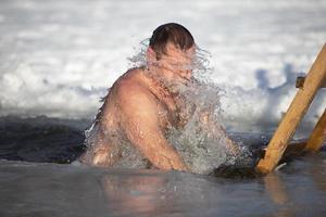 ein Mann stürzt in ein Eisloch während das Winter Festival von das Taufe von Jesus. ein Mann schwimmt im das Eisloch im Winter. Walross Personen. foto