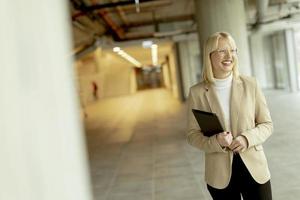 Geschäftsfrau mit digitalem Tablet auf modernem Büroflur foto