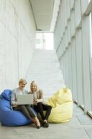 geschäftsfrauen, die laptop-computer auf faulen taschen im modernen büro verwenden foto